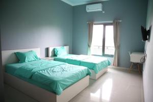 duas camas em um quarto com paredes azuis em Cemara Guest House Syariah Kertajati em Babakan