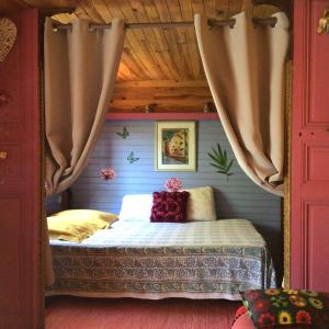 Roulotte Fenouillet في هييريس: غرفة نوم بسرير في غرفة مع ستائر