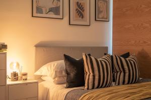 Una cama con almohadas blancas y negras. en The Works - Central Manchester Apartment - 2 Parking Spaces en Mánchester