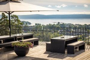 eine Terrasse mit Bänken und einem Sonnenschirm und Blick auf das Wasser in der Unterkunft Quality Hotel Leangkollen in Asker