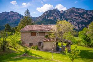 an old house in a field with mountains in the background at Complex Rural Can Caubet in Berga