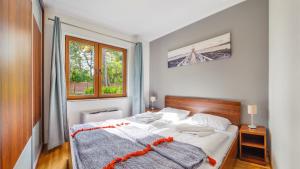 a bedroom with a bed and a window at Apartamenty Sun & Snow Villa Cztery Pory Roku in Jastrzębia Góra
