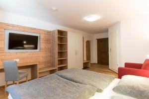 1 dormitorio con 1 cama y TV en la pared en Das Geringer, en Schladming