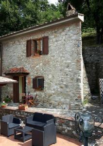 una casa de piedra con sillas y una mesa frente a ella en Cottage La Spagna, en Pistoia