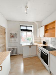 een keuken met witte kasten, een wastafel en een raam bij Finlandsgade 18 2th ID 047 in Esbjerg