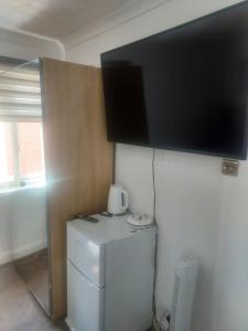 uma televisão na parede por cima de um frigorífico em Alder en-suite self caring private shower 2 em Southampton