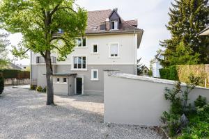 una casa blanca con un árbol en la entrada en "Urbaine Cosy" Elégance, confort et détente en Alsace "Les Péri-Urbaines", en Riedisheim