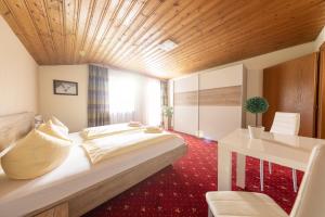 a bedroom with a large bed and a desk in a room at T3 Pension Wald am Arlberg in Wald am Arlberg