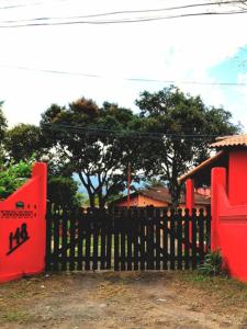 drewniany płot z czerwoną bramą przed domem w obiekcie Sitio148 Hospedaria w mieście Penedo