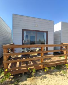 a deck with a table and chairs in front of a house at La Tribu Ecolodge y Camping in Algarrobo