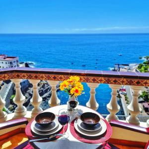 stół z dwoma kieliszkami wina na balkonie z widokiem na ocean w obiekcie FRONT LiNE OCEAN ViEW 2BeD Wi-Fi YOUR HOLiDAY HOME w mieście Puerto de Santiago