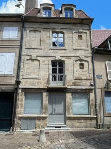 - un vieux bâtiment en pierre avec des fenêtres donnant sur une rue dans l'établissement LE CHAPITRE - Agréable maison de ville, à Autun