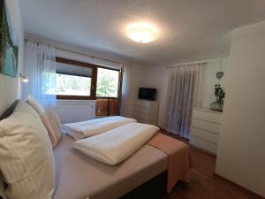 a bedroom with a bed with white sheets and a window at Ferienwohnung Sonja in Bach