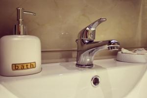 - un lavabo dans la salle de bains avec un distributeur de savon à côté d'un lavabo dans l'établissement SUNSET Luxury Accommodation, à Verga Kalamata