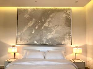 a large painting above a bed with two lamps at Al Majdiah 4-BD الماجدية ريزدينس شقة 4 غرف مطلّة - القيروان in Riyadh
