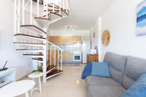 a living room with a couch and a spiral staircase at Home2Book Sea Front Duplex Terrace Pool in Puertito de Güímar