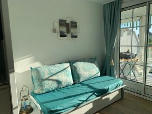 uma cama com almofadas azuis num quarto com uma varanda em Vue mer, superbe appartement refait à neuf! em Talmont