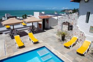 a pool with chairs and umbrellas next to a building at Santorini Praia Hotel in Natal