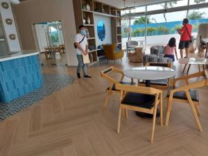 サンフェルナンドにあるSkycourt Suites at Azure North Pampanga Condominiumのテーブルと椅子の部屋に立つ男