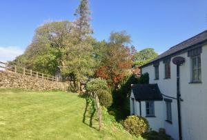 a yard with a house and a stone wall at High Ground Cottage, Eskdale in Eskdale