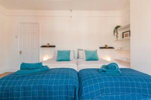 a bedroom with two beds with blue sheets at Chestnut House Exeter in Exeter