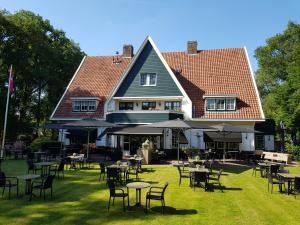 ダルフセンにあるHotel De Baronesの芝生の中にテーブルと椅子が置かれた大きな家