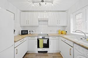 a white kitchen with white cabinets and a sink at CityStay 1 Bed Flat In Hendon- Free Parking in Colindale