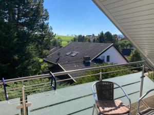 a chair on a balcony with a view of a house at FeWo Alkapa in Hilzingen