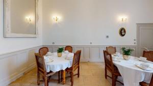 una sala da pranzo con tavoli e sedie con tovaglia bianca di La Templerie - Chambres d'hôtes a La Flèche