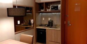 a small kitchen with a sink and a microwave at Brisas do Lago - Apartamento 2 in Brasilia
