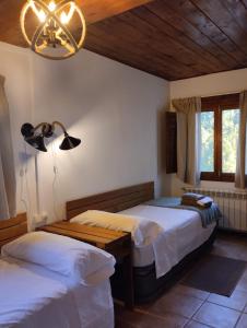 1 dormitorio con 2 camas y lámpara de araña en Masia La Clariana, en Castelltallat