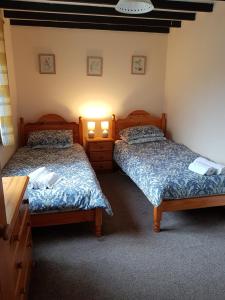 two beds in a room with two lamps on them at Blaencwm Cottages in Boncath