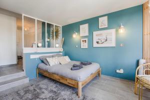 1 dormitorio con una pared azul y 1 cama en LA REV'RIE - vue sur mer avec balcon, en Deauville