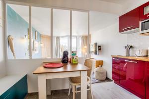 eine kleine Küche mit einem Holztisch und roten Schränken in der Unterkunft LA REV'RIE - vue sur mer avec balcon in Deauville