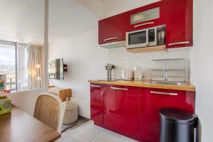 - une cuisine rouge avec évier et four micro-ondes dans l'établissement LA REV'RIE - vue sur mer avec balcon, à Deauville