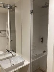 biała łazienka z umywalką i prysznicem w obiekcie Willa Pastel w mieście Białystok