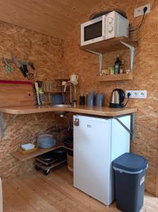 uma pequena cozinha com frigorífico e micro-ondas em La Roulotte Viticole - sauna - toilette sèche em Floreffe