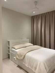 1 dormitorio con cama blanca y cortina en Lovely Continew Residence 2 Bedrooms - KL, en Kuala Lumpur