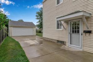 a house with a garage next to a driveway at Gorgeous 2 Bedroom Lower Apartment with Free Driveway Parking in North Buffalo in Buffalo