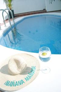 un cappello e un bicchiere di vino accanto alla piscina di Villa Casa Blanca ad Adeje