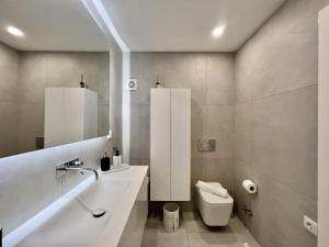 a white bathroom with a sink and a toilet at Quarteira Stylish by Homing in Quarteira