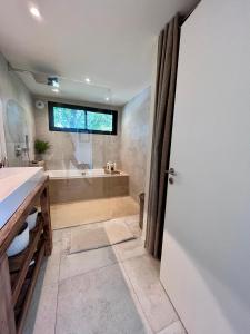 La salle de bains est pourvue d'une baignoire, d'un lavabo et d'une porte. dans l'établissement Belle Villa aux portes de Montpellier, à Montferrier-sur-Lez