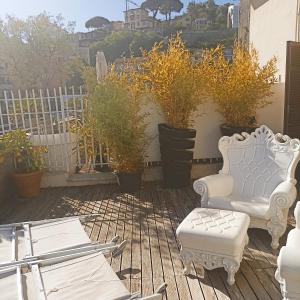 um pátio com duas cadeiras brancas e vasos de plantas em Casa Palmira em La Spezia