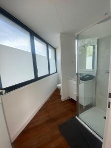 een badkamer met een glazen douche en een toilet bij La Résidence Amal in Talence