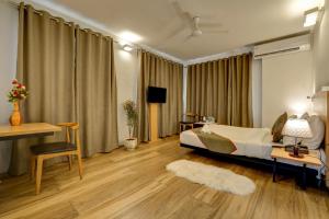 a bedroom with a bed and a table and a desk at Hotel Plaza Inn by Rio in Calangute