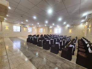 un salón de banquetes con sillas negras en una habitación en Hotel Nova Pride, en Rajkot