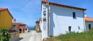 a white building with a sign on the side of it at Alojamientos playa del silencio in Castañeras