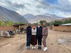 un groupe de trois personnes debout devant une montagne dans l'établissement Guesthouse Damira, à Kyzyloy