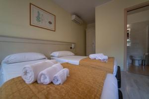 twee bedden in een hotelkamer met handdoeken erop bij Hotel Siros in Verona