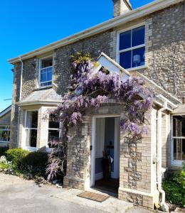 una casa con flores púrpuras en la puerta principal en Fairwater Head en Axminster